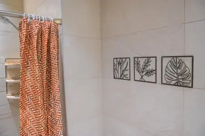 a bathroom with a shower curtain and four pictures on the wall at UrbanHomes - Cozy, Wooden and Travel Eco-Friendly Studio in Dubai