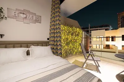 a bedroom with a bed and a chair on a balcony at UrbanHomes - Cozy Spacious Exceptional Studio in Heart of Dubai at JVC in Dubai