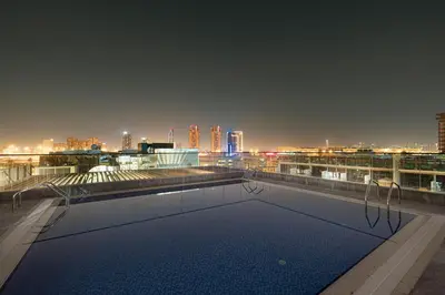 a swimming pool on top of a building with a city skyline at UrbanHomes - Cozy Spacious Exceptional Studio in Heart of Dubai at JVC in Dubai
