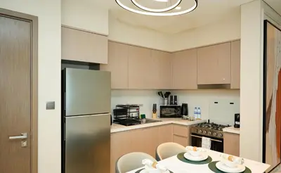 a kitchen with a refrigerator and a table with chairs at Chic 1BR Retreat , Blvd Views, Walk to Dubai Mall in Dubai