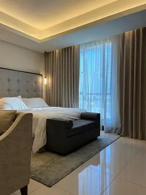 a bedroom with a bed and a couch in front of a window at The Address Downtown Studio 1911 in Dubai