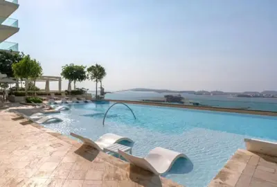 a swimming pool with white chairs in the water at Emaar Beachfront Luxe Retreat in Dubai