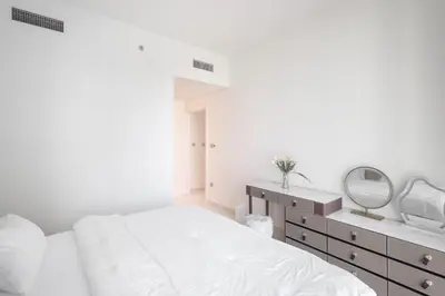 a white bedroom with a bed and a mirror at Emaar Beachfront Luxe Retreat in Dubai