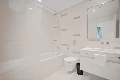 a white bathroom with a tub and a toilet and a sink at Emaar Beachfront Luxe Retreat in Dubai