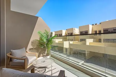 a balcony with chairs and a table and a building at Sleek Brand New Studio in Loci Residence JVC in Dubai