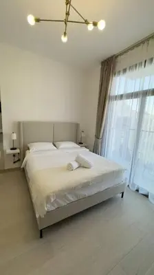 a white bedroom with a bed and a window at New! Modern cosy Studio Laya Heights in Dubai