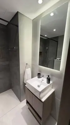 a bathroom with a sink and a shower and a mirror at New! Modern cosy Studio Laya Heights in Dubai