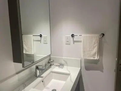 a white bathroom with a sink and a mirror at 'Dubai Creek Horizon Tower2' 1-Bedroom in Dubai