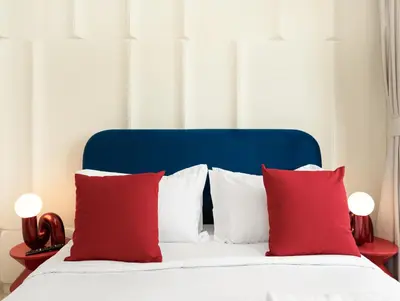 a bed with red pillows and a blue head board at Modern High-Floor Apartment with Burj Khalifa View by Dejaview Stays in Dubai
