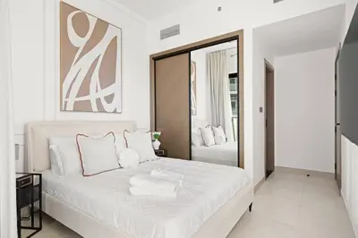 a white bedroom with a large white bed and a mirror at Binghatti Canal Business Bay in Dubai