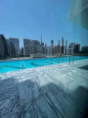 a large swimming pool with a city in the background at Binghatti Canal Business Bay in Dubai