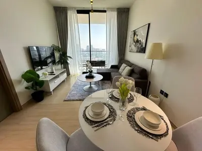 a living room with a table and chairs in a room at Elegant 1br Escape Jvc Pool & Balcony Access in Dubai