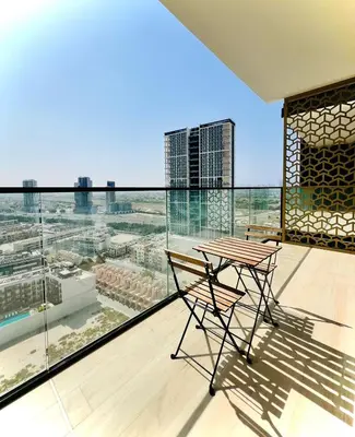 a table and chair on a balcony with a view at Modern Luxury Fully Furnished 1BH Apartment in Binghatt Emerald JVC - Easy Access to JBR, Circle Mall & Dubai Hills Mall in Dubai