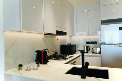 a kitchen with white cabinets and a stove top oven at Modern Luxury Fully Furnished 1BH Apartment in Binghatt Emerald JVC - Easy Access to JBR, Circle Mall & Dubai Hills Mall in Dubai