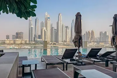 a pool with chairs and umbrellas and a city skyline at Private Beach & Canal View-Top Location-Pool-Gym in Dubai