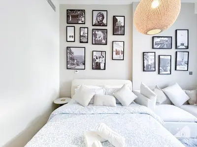 a bedroom with a white bed with pictures on the wall at Meydan Bliss Luxurious Studio with Private Balcony in Dubai