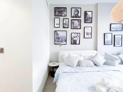 a bedroom with a white bed and framed pictures on the wall at Meydan Bliss Luxurious Studio with Private Balcony in Dubai