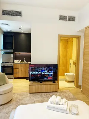 a living room with a television and a kitchen at Cozy Studio JVC Dubai, Short Drive to Dubai Marina, JBR, Downtown Dubai in Dubai
