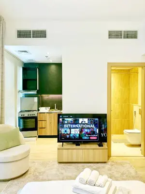 a living room with a tv and a kitchen at Cozy Studio JVC Dubai, Short Drive to Dubai Marina, JBR, Downtown Dubai in Dubai