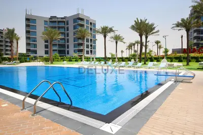 a large swimming pool with chairs and a building at Charming 2BR at MAG 515 Dubai South by Deluxe Holiday Homes in Dubai
