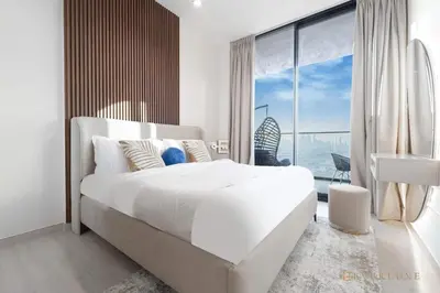 a white bedroom with a large bed and a large window at 1BR Gem in JVC Pool, Gym, BBQ & Balcony in Dubai