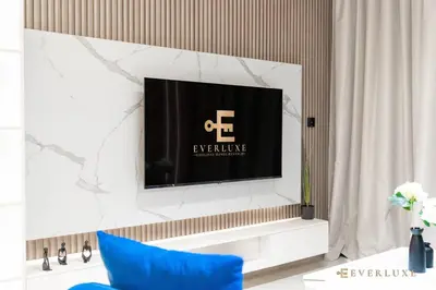a living room with a tv on a wall at 1BR Gem in JVC Pool, Gym, BBQ & Balcony in Dubai