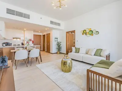 a living room with a white couch and a kitchen at Elegant One Bed Apartment - Hameni Tower,JVC in Dubai