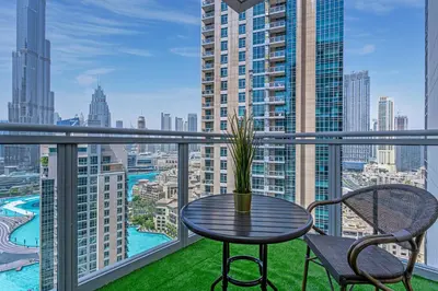 a table and chairs on a balcony with a view of a city at Savis Homes - Luxury 2 Bedroom Suite with Full Burj Khalifa View in Dubai