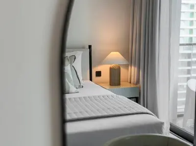 a bedroom with a bed and a lamp and a window at HiGuests - Elegant 2-Bedroom Retreat at Marina Vista 2 in Dubai