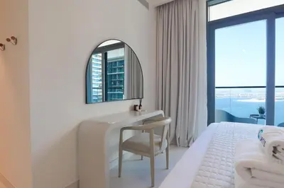 a white bedroom with a desk and a mirror at HiGuests - Elegant 2-Bedroom Retreat at Marina Vista 2 in Dubai