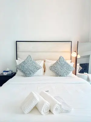 a white bed with two pairs of slippers on it at Elegant Studio Stay near Miracle Garden, Butterfly Garden & Dubai Hills Mall in Dubai