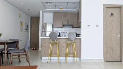 a kitchen with two bar stools and a table at Fully Furnished 1BR Close by Dubai Science Park, Dubai Miracle Garden, Dubai Hills Mall in Dubai