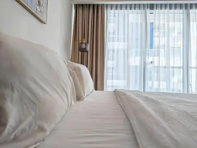 a bed with white pillows in a room with a window at Fully Furnished 1BR Close by Dubai Science Park, Dubai Miracle Garden, Dubai Hills Mall in Dubai