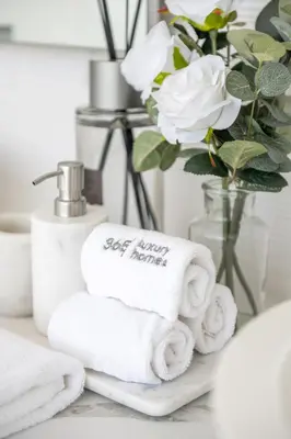 a pile of towels on a bathroom counter with a vase with flowers at Ultra-Luxury 6BR Palm Villa - Private Pool & Beach in Dubai