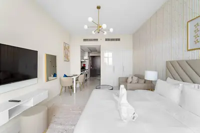 a white bedroom with a large bed and a living room at FIRST CLASS Studio Luxury Getaway in Dubai