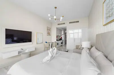 a white bedroom with a bed and a tv at FIRST CLASS Studio Luxury Getaway in Dubai
