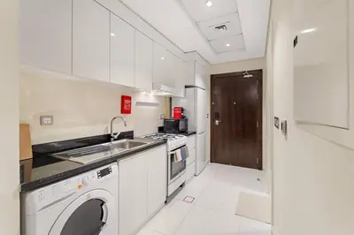 a white kitchen with a sink and a dishwasher at FIRST CLASS Studio Luxury Getaway in Dubai