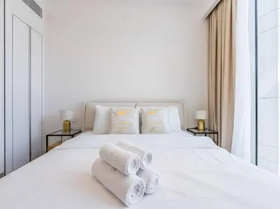 a bedroom with a white bed with towels on it at Modern Spacious- 2 BR with Pool & Gym- Luma 22 JVC in Dubai