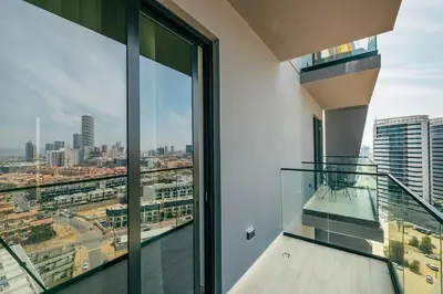 an apartment balcony with glass doors and a view of a city at Beautiful 1BR - City View - Pool - Free Parking in Dubai
