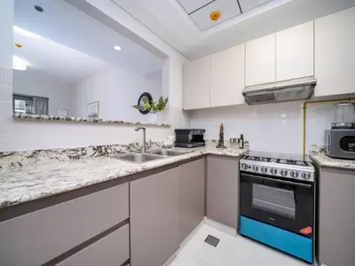a kitchen with white cabinets and a sink and a stove at Chic 1 Bed Getaway in Al Jaddaf Easy City Access in Dubai