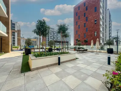 a courtyard with benches and tables and buildings at Elegant Studio in Azizi Riviera, Meydan in Dubai