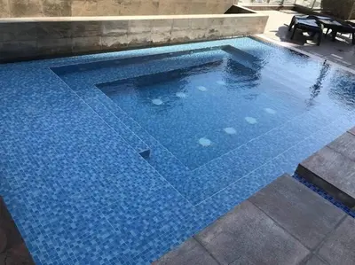 a large swimming pool with blue tiles on the ground at Lux apartments x Dubai studio 22 in Dubai