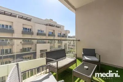 a balcony with two chairs and a table and a building at Large studio in JVC - Dubai in Dubai
