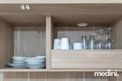 a wooden cabinet with plates and glasses and dishes at Large studio in JVC - Dubai in Dubai