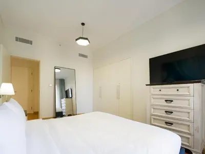 a bedroom with a white bed and a flat screen tv at EasyGo- amazing 1bdr with view south ridge- downtown in Dubai