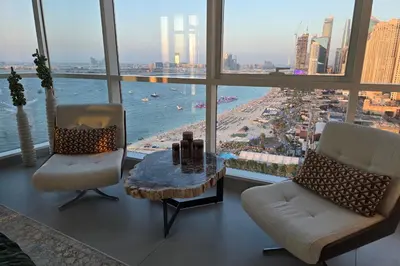 a living room with two chairs and a table in front of a window at Beachfront 250 view private beach high floor in Dubai