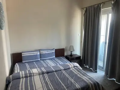a bedroom with a bed with blue and white sheets and a window at Marina, Beach & Mall Walking Dis in Dubai