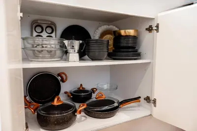 a cupboard filled with pots and pans and plates at Large 2BR with Marina and Sea View in 5242 Tower - EE Holiday Homes in Dubai