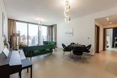 a living room with a table and a green couch at Large 2BR with Marina and Sea View in 5242 Tower - EE Holiday Homes in Dubai