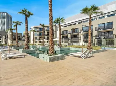 a courtyard with chairs and palm trees in front of a building at Luxury Apartment in Oakley Square Residences, JVC in Dubai